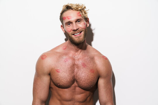 White shirtless man with lipstick marks smiling and looking at camera