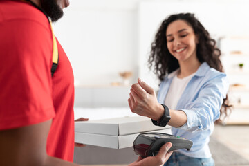 Black delivery man holding pizza box and pos terminal