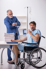 Young male employee in wheel-chair feeling bad at workplace