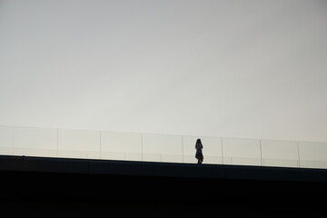 silhouette of a female walking on a bridge