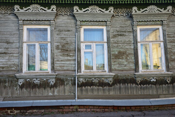 Orel city. In a 19th century building, three windows of the house are decorated with protective wood carvings
