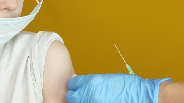 Close-up shot of a Caucasian school-age boy being given the vaccine. Mandatory vaccination. The injection is in the hands of the doctor. The child is given a vaccination in the shoulder at the clinic.