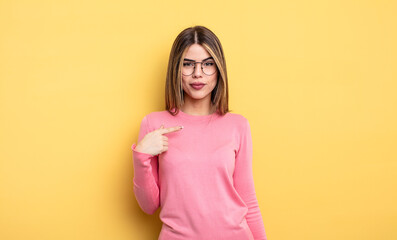 pretty caucasian woman looking proud, confident and happy, smiling and pointing to self or making...