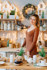 attractive woman in brown dress in New Year's kitchen with cup in hands