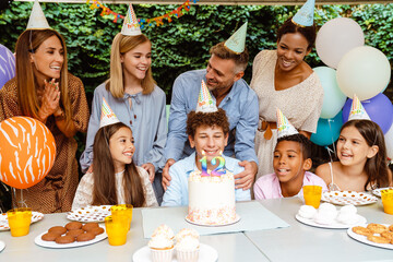 White curly boy celebrating birthday with his parents and friends