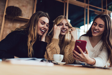 Female friends enthusiastically watching video on smartphone