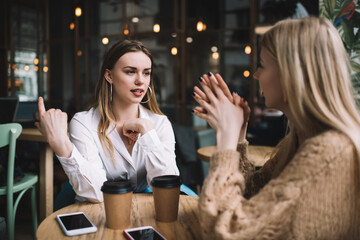 Young female coworkers discussing work plan while sitting in cafeteria