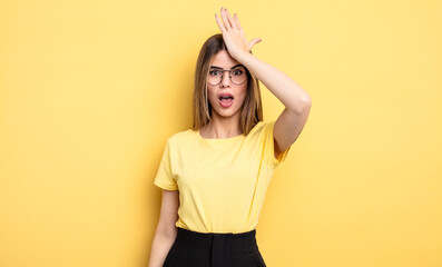 pretty caucasian woman raising palm to forehead thinking oops, after making a stupid mistake or...