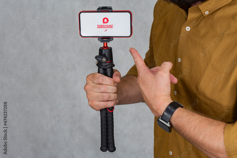 Poster subscribe to the internet channel on the smartphone display on a flexible tripod on a gray backgroun