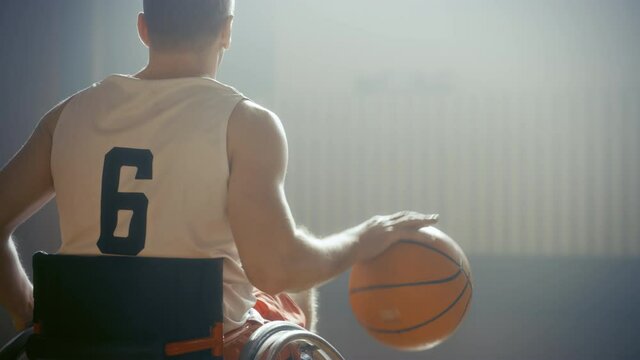 Wheelchair Basketball Player Dribbling Ball Like a Professional, Ready to Shoot and Score Goal. Determination, Motivation of a Person with Disability Excelling at Team Sport. Back View, Slow Motion