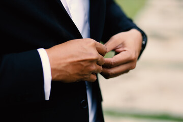 The groom tightens his cufflinks before the wedding