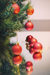 Decorative Christmas red balls hanging on a branch reflected in a mirror 