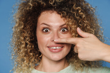 Young surprised woman in t-shirt pointing finger at her nose