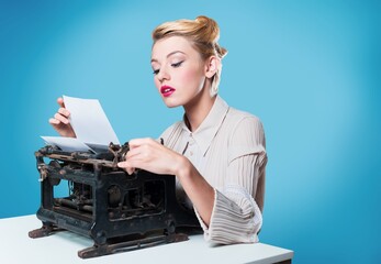 young woman writer at a typewriter, writing a text. Young at a table with a vintage typewrite