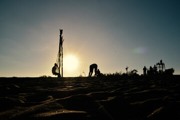 Silhouettes of people playing on the beach in the morning