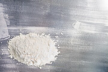 Pile of flour, on dark or black background. Spilled flour. Flour texture.