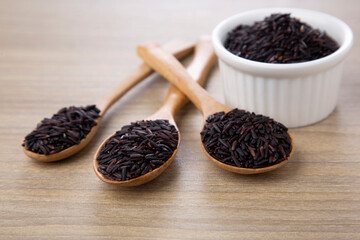rice berry rice in wood spoon and white bowl on wood table