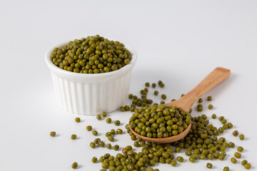mung bean in bowl and wood spoon on pile of mung bean white background studio shot