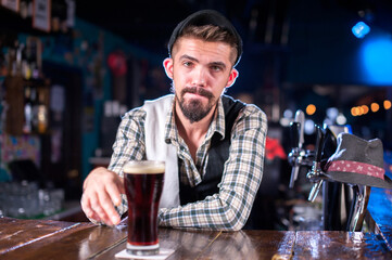 Bearded barman decorates colorful concoction while standing near the bar counter in nightclub
