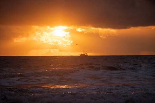 A Boat Sails Into The Sun During Early Morning Sunrise On Daytona Beach, Florida.