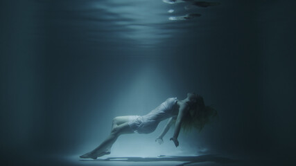 girl in a white dress swims underwater
