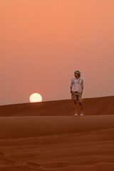 Fototapeta na wymiar Photo of a woman in a desert at sunset with the sun in the background