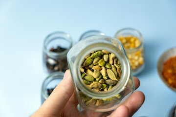 Close-up, a man holding a jar with dry useful herb for brewing.A jar of Cardamon spices