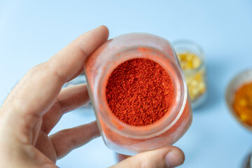 Close-up, a man holding a jar with dry useful herb for brewing. Red paprica