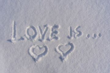 Two heart shape and text love is on a white fresh snow in winter, close up