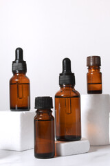 A mock-up of an empty glass dropper bottle made of brown glass stands on a white podium and a white background. Skin care serum, banner or template. The concept of a natural cosmetic product.Copyspace