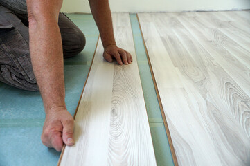 a worker assembles a laminate floor in a living room