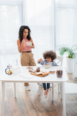 African american family eating breakfast near chocolate paste and bread at home.