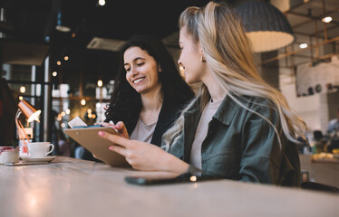 Cheerful women with clipboard having break in coffee shop