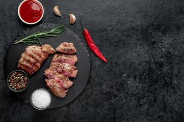 two grilled beef steaks with spices on a stone background with copy space	