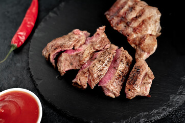 two grilled beef steaks with spices on a stone background