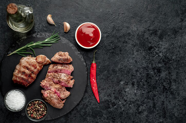 two grilled beef steaks with spices on a stone background with copy space	