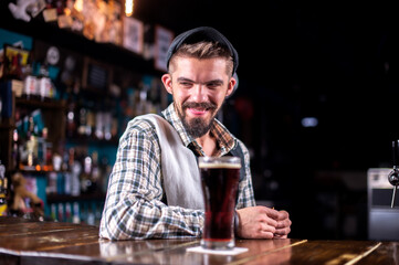 Charming barman pouring fresh alcoholic drink into the glasses in the nightclub