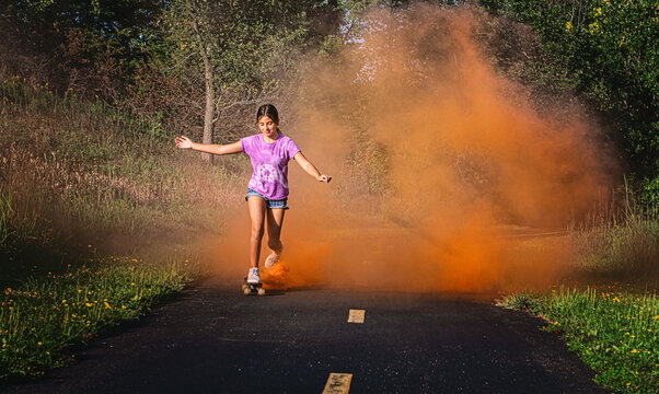 Happy tween girl skateboarding with smokebomb.
