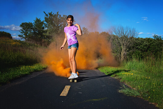 Happy tween girl skateboarding with smokebomb.