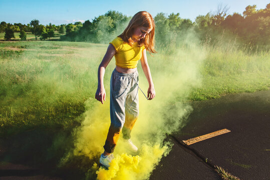 Cool tween girl skateboarding with smokebomb.