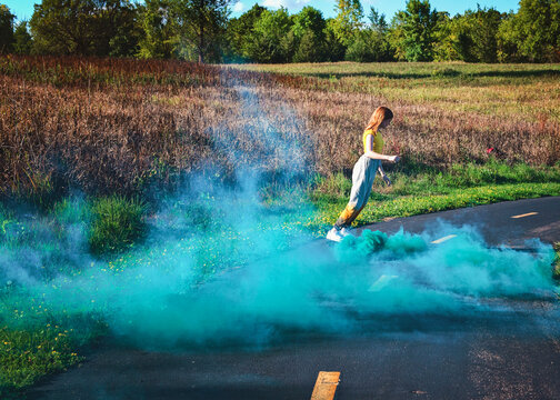 Happy tween girl skateboarding with smokebomb.