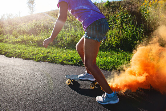 Happy tween girl skateboarding with smokebomb.