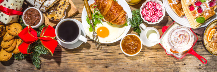 Festive Christmas morning breakfast or brunch table, with traditional foods – pancakes, Belgian waffles, fried eggs, croissant, stolen, cookies, with orange juice and coffee, cinnamon rice porridge 