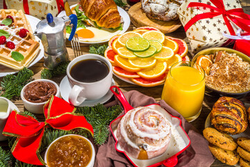 Festive Christmas morning breakfast or brunch table, with traditional foods – pancakes, Belgian waffles, fried eggs, croissant, stolen, cookies, with orange juice and coffee, cinnamon rice porridge 