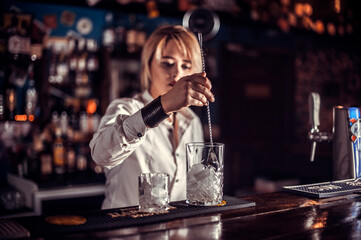 Focused woman barman decorates colorful concoction