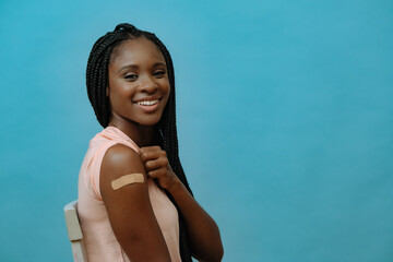 Vaccinated attractive young woman with plaster on hand - obrazy, fototapety, plakaty