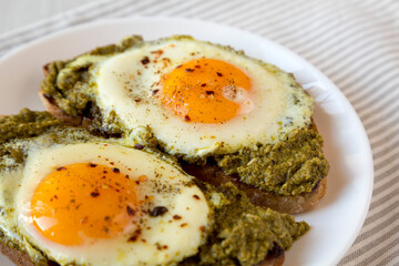 Homemade Pesto Egg Toast on a white plate, low angle view. Close-up.