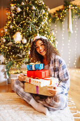 Fototapeta na wymiar Young woman with Christmas gifts at home near Christmas tree. Winter holidays. New Years.