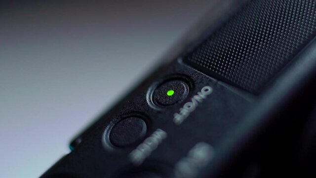 the finger presses the on off button of the video camera and the green light turns on. Close-up