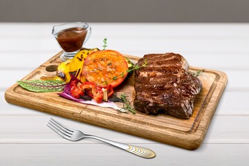 Grilled beef steak on a wooden board with grilled vegetables. Filet recipe concept,